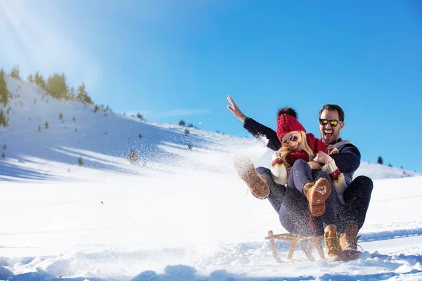 Pareja joven en trineo y disfrutando en el soleado día de invierno —  Fotos de Stock