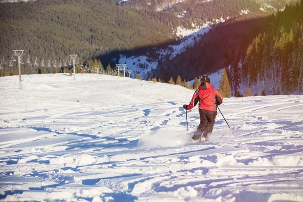 Esquiador esquiando cuesta abajo en las altas montañas contra el atardecer — Foto de Stock