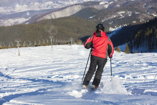 Esquiador esquiando cuesta abajo en las altas montañas contra el atardecer — Foto de Stock