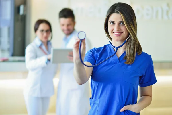 Jovem médico feminino atraente na frente do grupo médico . — Fotografia de Stock