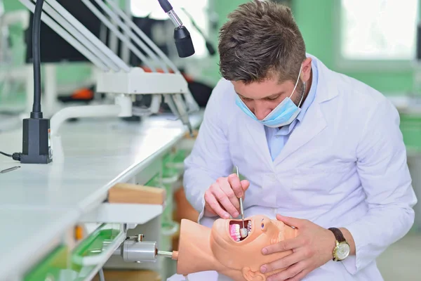 Estudante de odontologia do sexo masculino praticando boneca na clínica moderna . — Fotografia de Stock