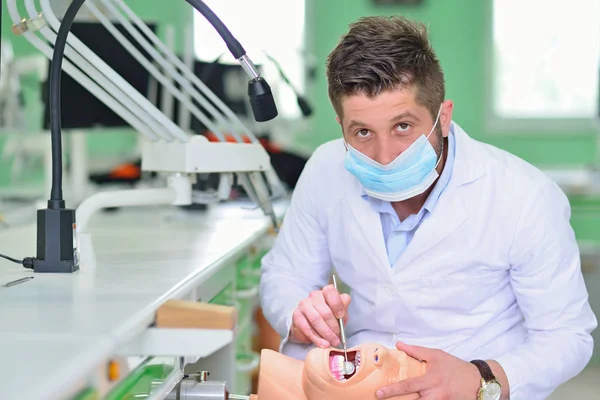 Estudante de odontologia do sexo masculino praticando boneca na clínica moderna . — Fotografia de Stock