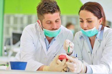 Diş protezleri, protezler, protezler. Takma diş üzerinde çalışırken protez eller.