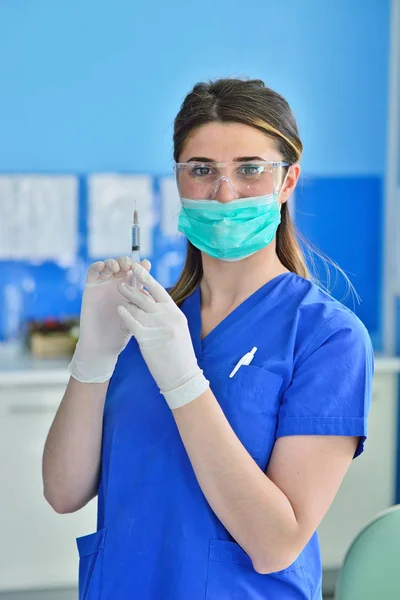 Dentista que sostiene un modelo de estudio de odontología y una jeringa — Foto de Stock