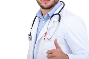 Başarılı genç yakışıklı ve şık sakallı doktor başparmak yukarıya ile beyaz arka plan, beyaz üniforma ayakta.
