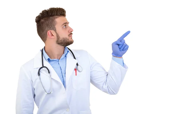 Портрет молодого улыбающегося мужчины-врача, показывающего пальцем на белом фоне — стоковое фото