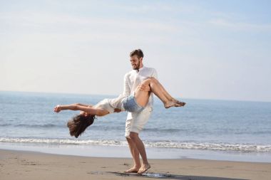 Mutlu, genç, romantik bir çift güzel bir kumsalda, güzel bir yaz gününde eğleniyor..