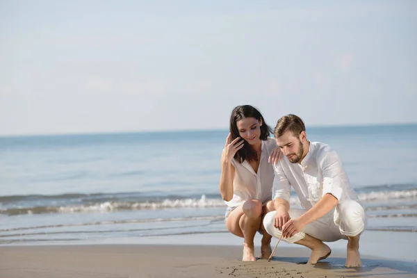 Romantische jong koppel tekenen hart vormen in het zand terwijl op huwelijksreis. zomer strand liefde concept. — Stockfoto