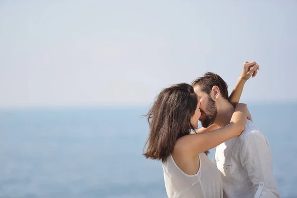 Romántica pareja joven en la playa besándose . — Foto de Stock