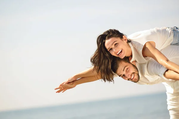 Et bilde av et lykkelig par som har det gøy på stranden – stockfoto