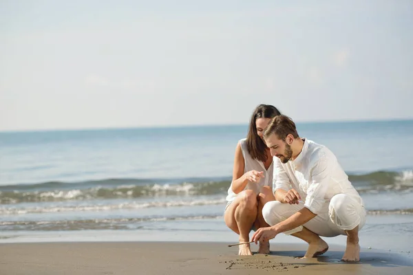 Romantische jong koppel tekenen hart vormen in het zand terwijl op huwelijksreis. zomer strand liefde concept. — Stockfoto
