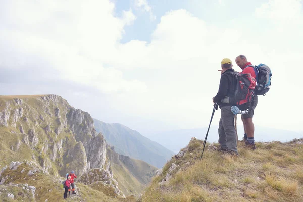 Turisté s batohy relaxaci na vrcholu hory a těší pohled do údolí — Stock fotografie