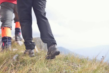 Bacaklar genç yürüyüşçü ülke yolda yürürken close-up. Genç iz uyanma çift. Ayakkabı hiking üzerinde odaklanmak