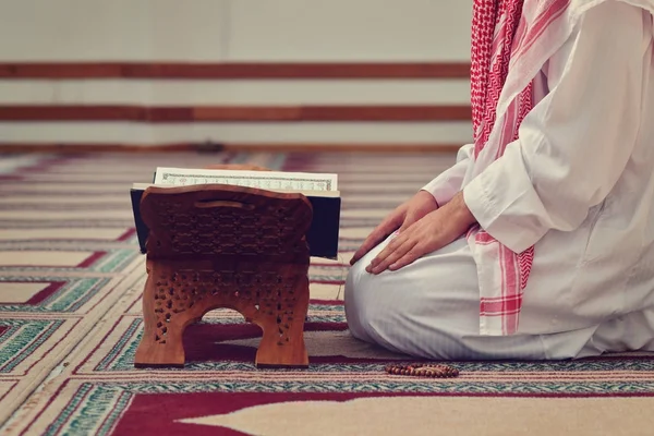 Un sagrado quran abierto con soporte de madera con gente rezando en el fondo — Foto de Stock