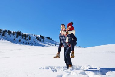 Genç çift kar üzerinde eğleniyor. Sırtıma binmek gülümseyen kız arkadaşına veren Mountain mutlu adam.