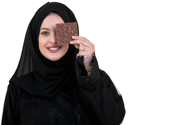 Прекрасная улыбающаяся мусульманка с хиджабом, поедающая шоколад на белом фоне . — стоковое фото