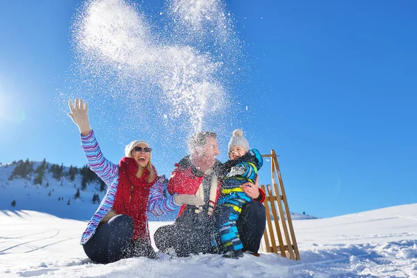 Jonge en gelukkige familie spelen in verse sneeuw op mooie zonnige winterdag die buiten in de natuur — Stockfoto