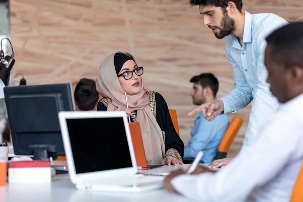 diverse college students using laptop and talking, learning exchanging ideas