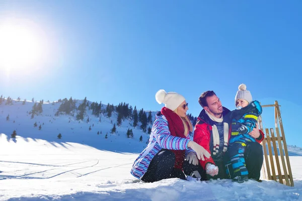 Feliz jovem família jogando na neve fresca no belo dia ensolarado de inverno ao ar livre na natureza — Fotografia de Stock