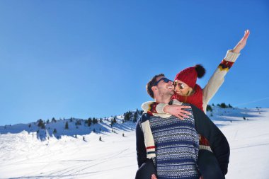 Genç çift kar üzerinde eğleniyor. Sırtıma binmek gülümseyen kız arkadaşına veren Mountain mutlu adam.
