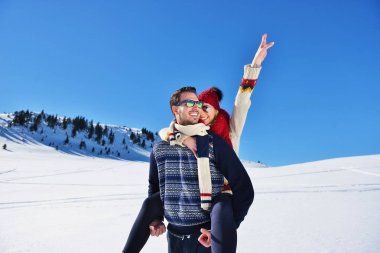 Genç çift kar üzerinde eğleniyor. Sırtıma binmek gülümseyen kız arkadaşına veren Mountain mutlu adam.