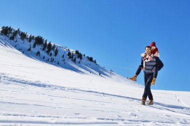 Genç çift kar üzerinde eğleniyor. Sırtıma binmek gülümseyen kız arkadaşına veren Mountain mutlu adam.