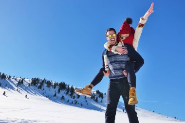 Genç çift kar üzerinde eğleniyor. Sırtıma binmek gülümseyen kız arkadaşına veren Mountain mutlu adam.