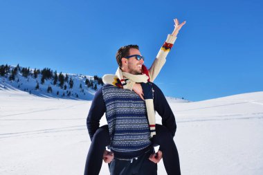 Genç çift kar üzerinde eğleniyor. Sırtıma binmek gülümseyen kız arkadaşına veren Mountain mutlu adam.