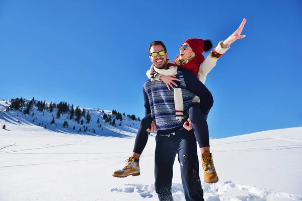 Genç çift kar üzerinde eğleniyor. Sırtıma binmek gülümseyen kız arkadaşına veren Mountain mutlu adam. — Stok fotoğraf