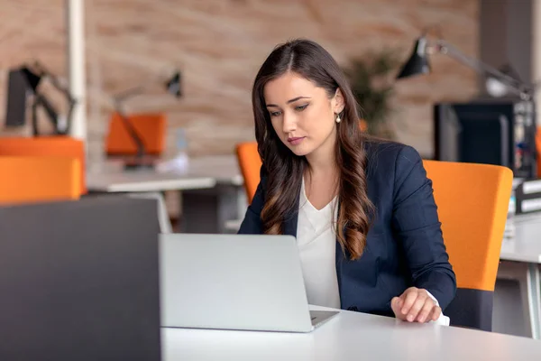 Młoda kobieta korzysta z laptopa w biurze tabeli — Zdjęcie stockowe