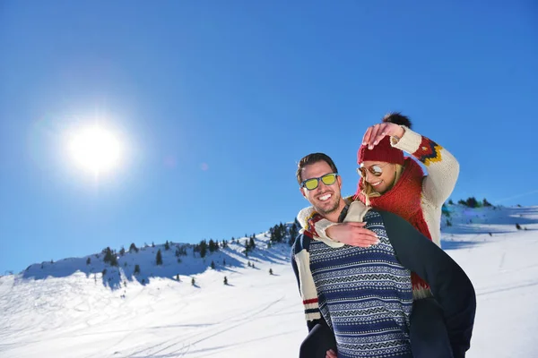 Молодая пара веселится на снегу. Счастливый человек в горах катает на спине свою улыбающуюся подружку . — стоковое фото