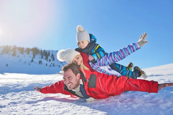 Feliz jovem família jogando na neve fresca no belo dia ensolarado de inverno ao ar livre na natureza — Fotografia de Stock