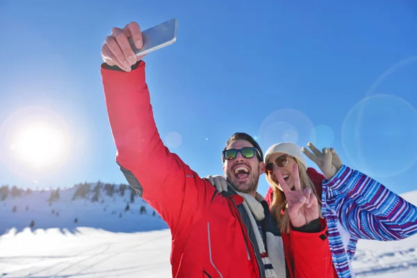 Happy couple taking picture with smartphone selfie stick on over winter background — Stock Photo, Image