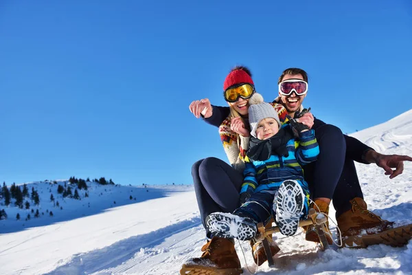 Счастливая молодая семья, играющая в свежем снегу в красивый солнечный зимний день на природе — стоковое фото