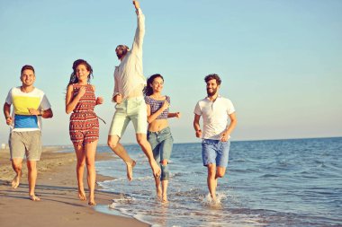 Arkadaşlar eğlence günbatımı güneş ışığı altında sahilde.