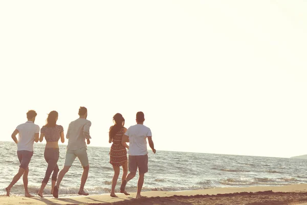 Amusement des amis sur la plage sous la lumière du soleil couchant . — Photo