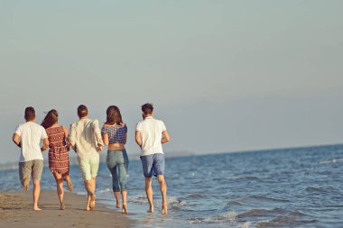 Arkadaşlar eğlence günbatımı güneş ışığı altında sahilde.
