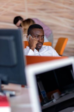 Neşeli siyah adam onun iş yerinde, kollarını başının arkasında onun laptop ekranında izliyor.