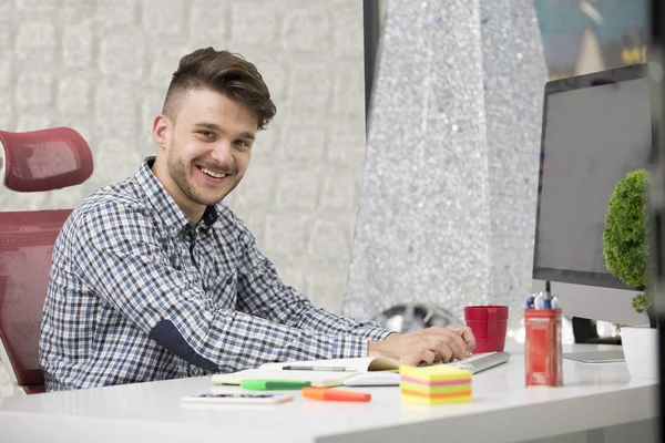 Man taking notes down from his new laptop computer at work in the morning office with coffee — Stock Photo, Image