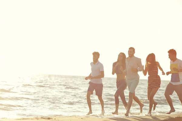 Amici divertimento sulla spiaggia sotto la luce del sole del tramonto . — Foto Stock