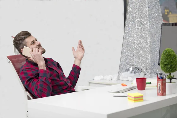 Guapo joven hablando por teléfono mientras hace papeleo en el lugar de trabajo —  Fotos de Stock