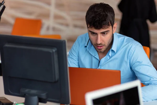 Крупный план шокированного молодого человека, работающего над ноутбуком — стоковое фото