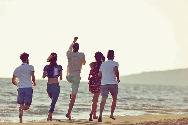 Amici divertimento sulla spiaggia sotto la luce del sole del tramonto . — Foto Stock