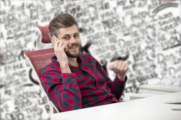 Guapo joven hablando por teléfono mientras hace papeleo en el lugar de trabajo —  Fotos de Stock