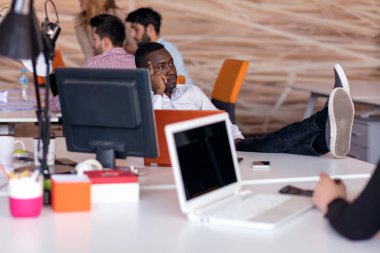 Neşeli siyah adam onun iş yerinde, kollarını başının arkasında onun laptop ekranında izliyor.