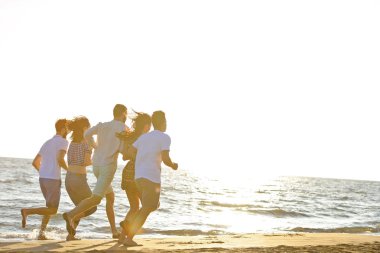 Arkadaşlar eğlence günbatımı güneş ışığı altında sahilde.