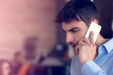 Modern ofis alanı içinde duran cep telefonu konuşurken neşeli bir gülümseyen adam ofis çalışanı portresi