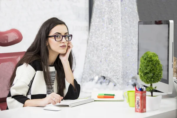 Portrait de belle jeune femme d'affaires brune souriante assise au poste de travail moderne lumineux et tapant sur un ordinateur portable — Photo