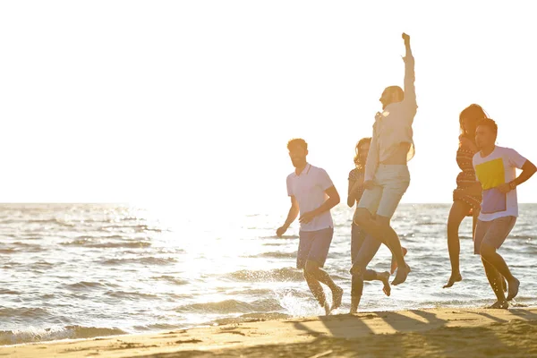 Vänner roliga på stranden under solnedgången solljus. — Stockfoto