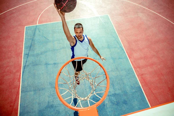 Vista de alto ângulo do jogador de basquete mascando basquete em aro — Fotografia de Stock